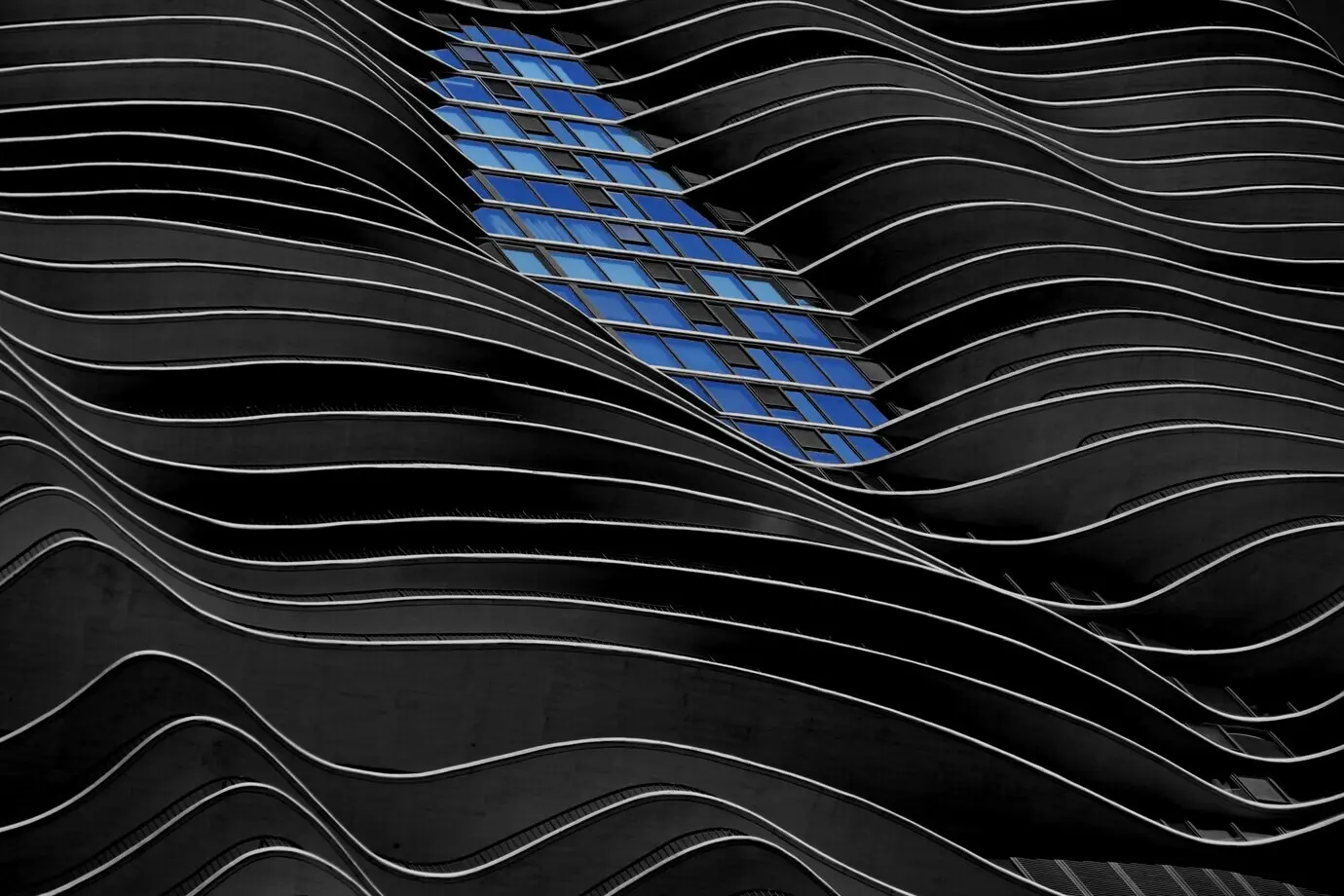 Gebäude im modernen Stil mit geschwungenen, schwarzen Wänden und leuchtend blauen Fenstern.